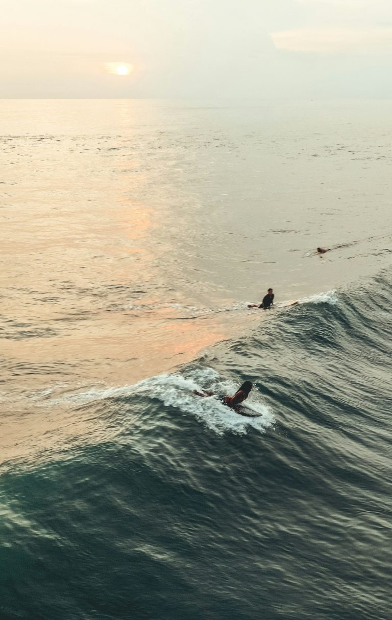 Surfers catching waves at sunset in Canggu, Bali